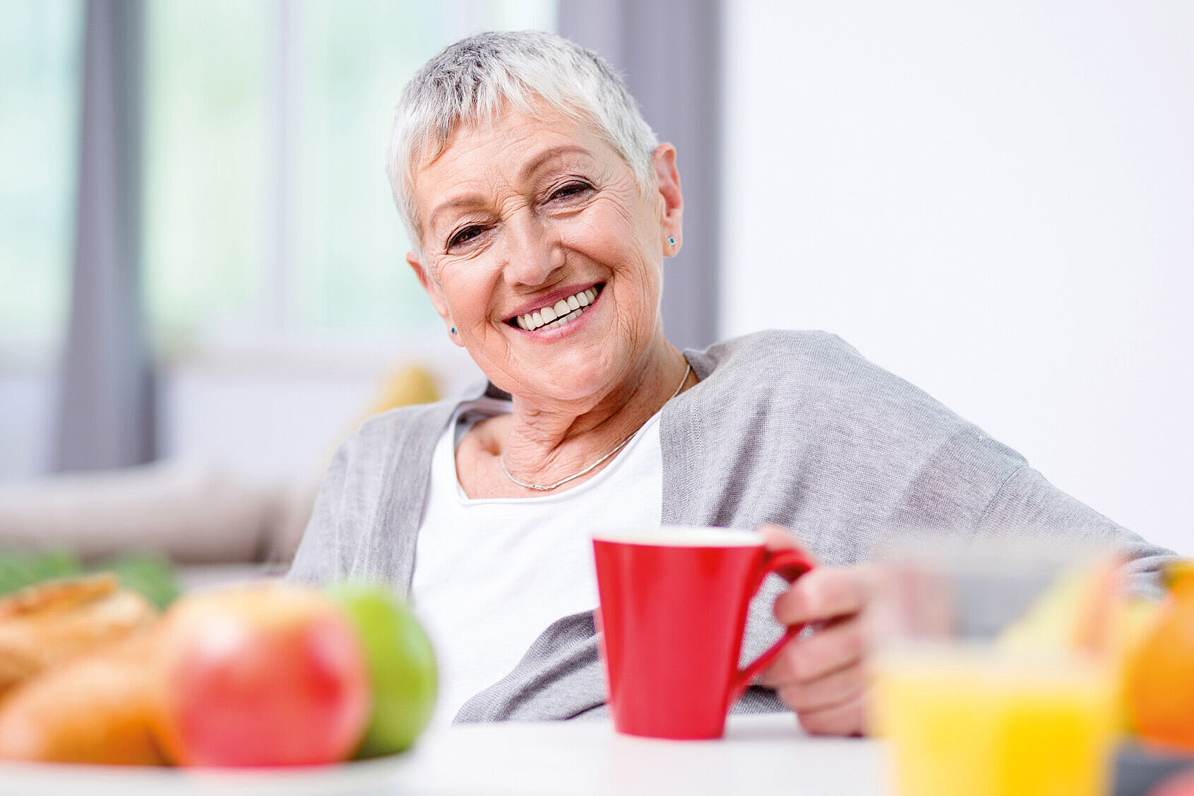 Seniorin mit Kaffeetasse am Frühstückstisch